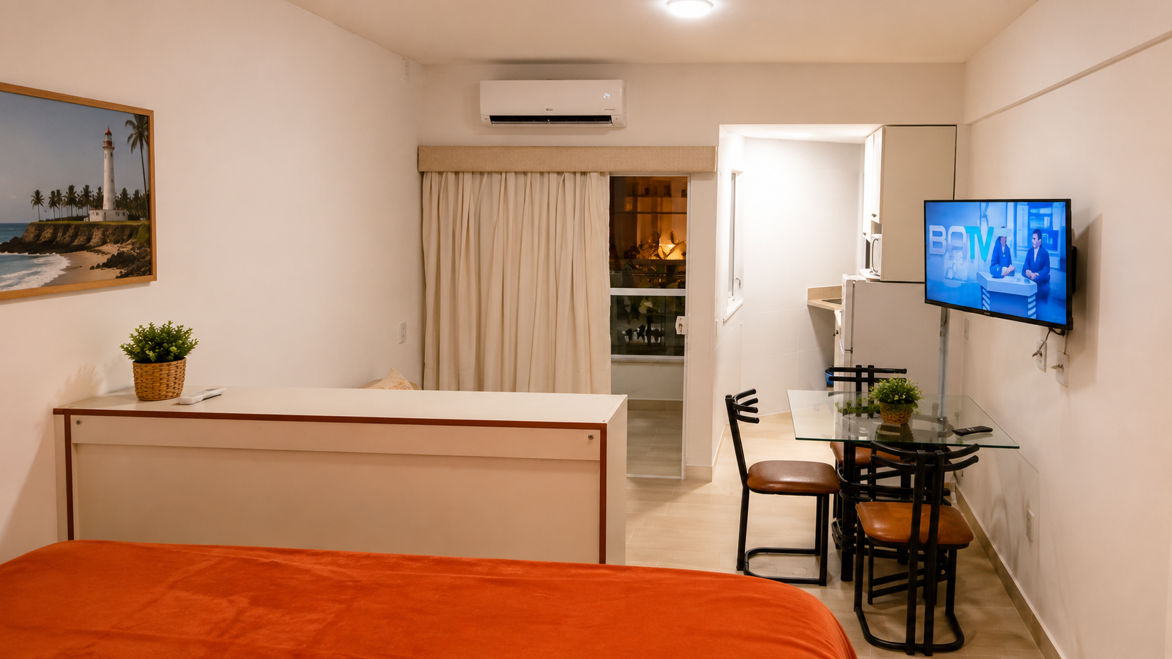 Sala de estar do apartamento no Bahia Flat, na Barra, Salvador, com sofá, ar-condicionado, Smart TV, mesa de jantar e cozinha integrada.
