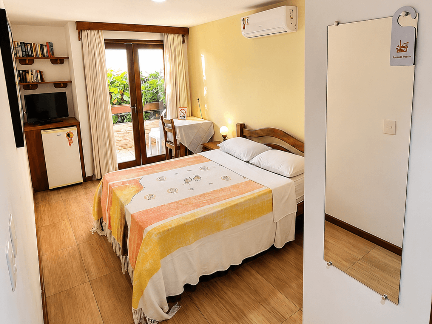 Quarto Lateral Duplo Standard da Pousada Poesia, com cama de casal, decoração aconchegante, mesa de apoio e acesso à varanda.
